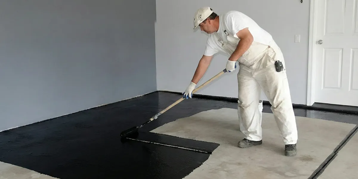 basement waterproofing professional applying waterproof coating to protect a basement floor in Boulder, CO
